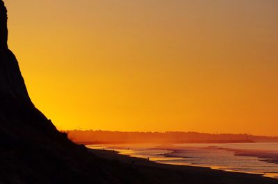 Scenic view of beach against orange sky