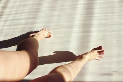 Low section of woman walking on floor in sunlight