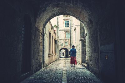 Rear view of woman standing on footpath in city