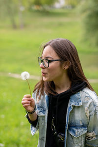 Beautiful young woman with eyeglasses standing against plants