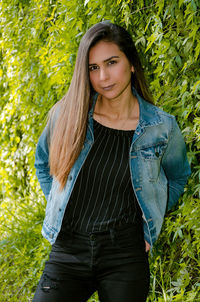 Portrait of beautiful young woman standing against plants