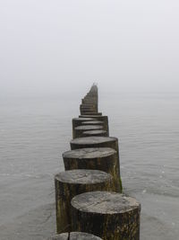 Wooden posts in sea against sky