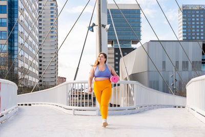 Young woman in sports clothing on footbridge