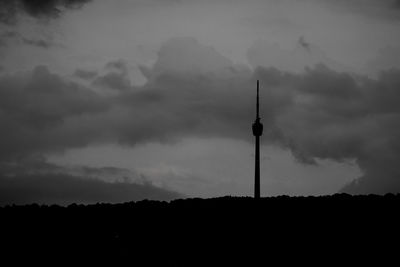 Low angle view of communications tower against cloudy sky