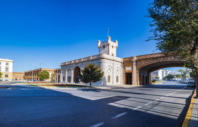 Street amidst buildings against blue sky