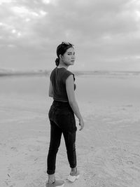 Side view of young woman standing at beach