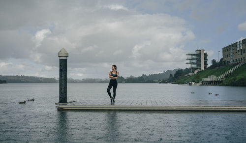 Woman standing on riverbank against sky