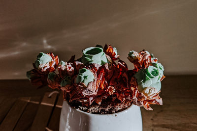Close-up of flowering plant on table against wall
