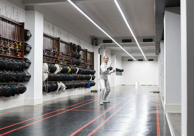 Woman in fencing outfit practicing at gym