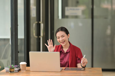 Young woman using phone while sitting on table