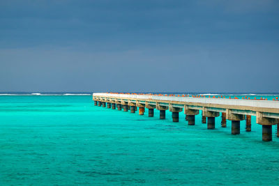 Pier over turquoise color sea against sky