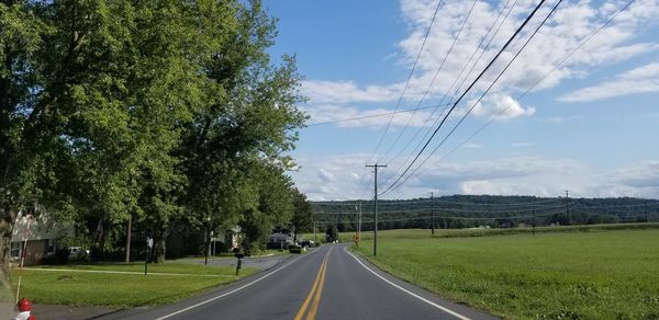 Road by trees against sky