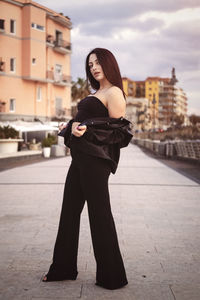 Portrait of young woman standing in city