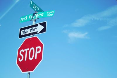 Low angle view of road sign against blue sky