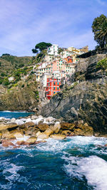 Buildings by sea against sky