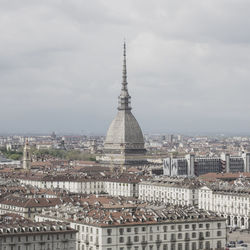 Aerial view of buildings in city against cloudy sky