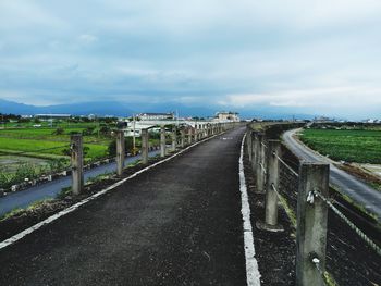 Road amidst field against sky