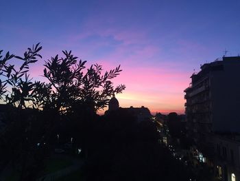 Silhouette trees and buildings against sky at sunset