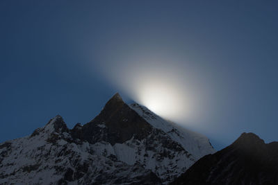 Scenic view of snowcapped mountains against clear sky at sunrise