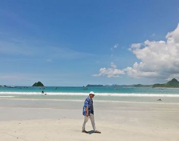 Rear view of woman standing on beach against sky
