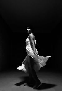 Woman wearing dress dancing in darkroom