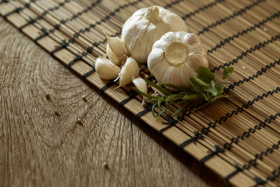 High angle view of garlic and peppercorns with herbs on wooden table