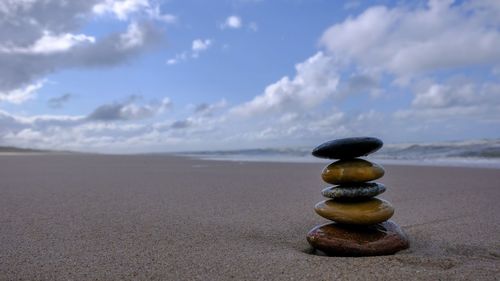 Stack of pebbles on beach against sky