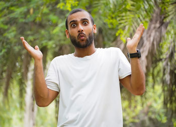 Portrait of young man standing against trees