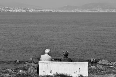 Rear view of couple sitting on sea shore