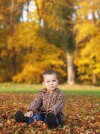 Smiling cute boy sitting on leaves at park