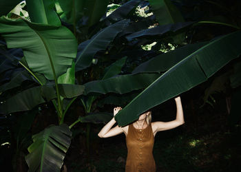 Woman covering face with banana leaf