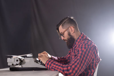 Young man using mobile phone against black background