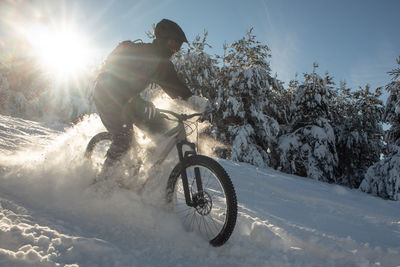 Man riding bicycle on snow covered land