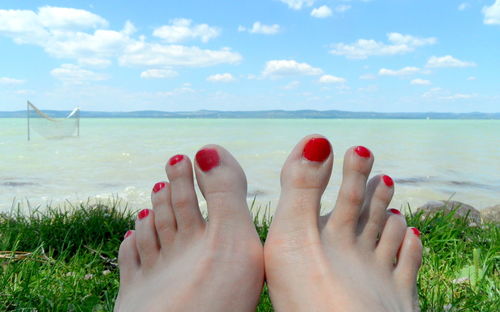 Low section of woman feet in sea against sky