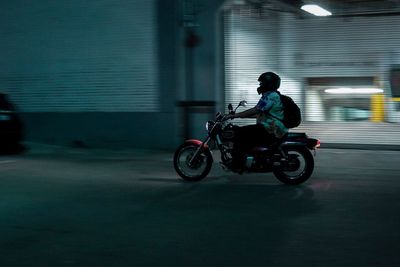 Blurred motion of man riding motorcycle on road at night