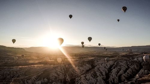 Hot air balloons flying over landscape against sky during sunset