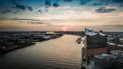 River amidst buildings against sky during sunset