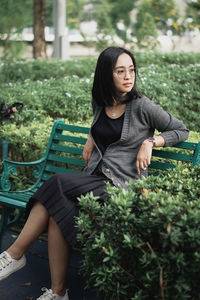 Young woman using mobile phone while sitting on field