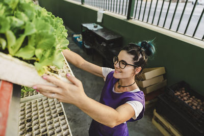 Smiling businesswoman carrying plants in nursery