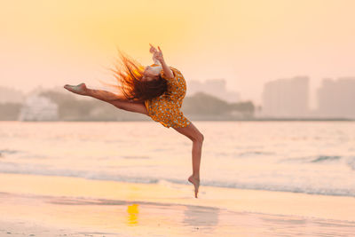 Woman on beach against sky during sunset