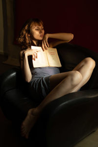 Woman sitting with book at home