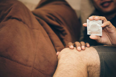 Close-up up couple holding condom lying on bed at home