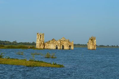 Castle by sea against clear blue sky