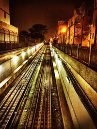 Railroad tracks against sky at night