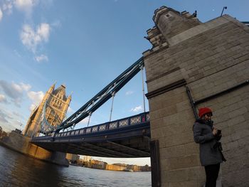 Low angle view of man standing by bridge against sky