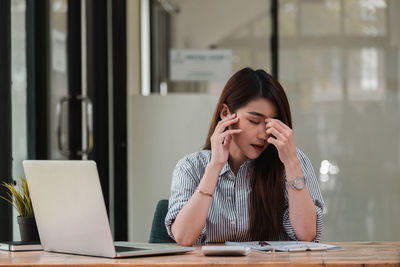 Young woman using phone while sitting on table