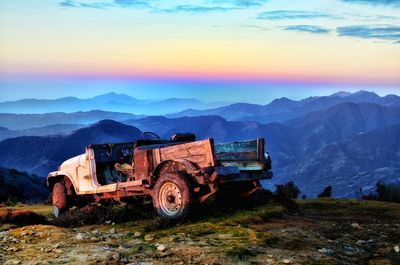 Built structure on landscape against sky at sunset