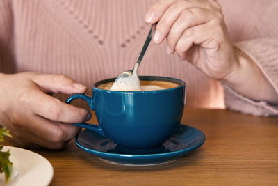 Close-up of hand holding coffee on table