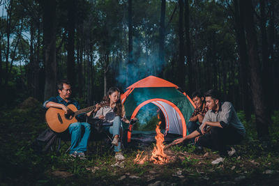 Friends around campfire enjoying in forest