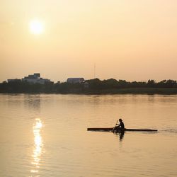 Man rowing raft in lake during sunrise